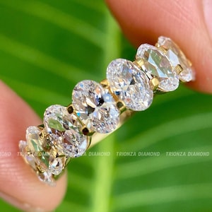 May include: A gold band ring with a row of oval-shaped diamonds set in a pave setting.