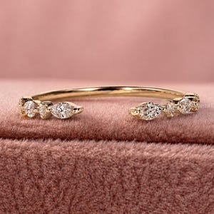 May include: A gold open-style ring featuring a series of small, clear, marquise and round-cut stones set along the two ends of the band. The band is thin and polished, showcasing a delicate design with sparkling accents on both sides.