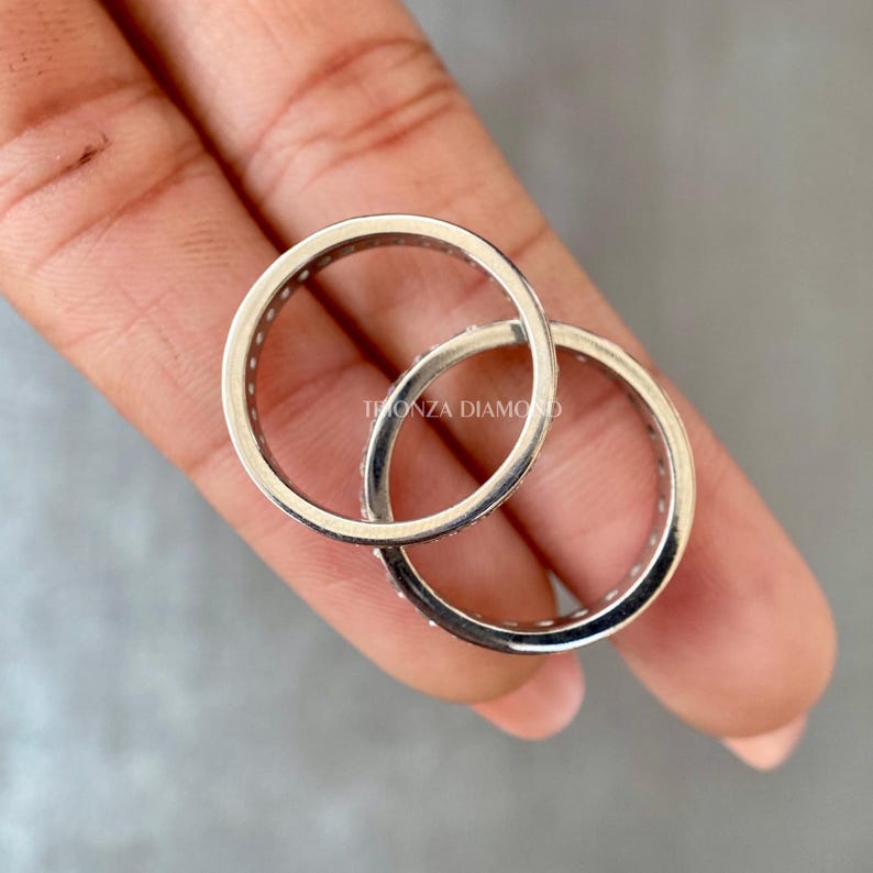May include: Two silver rings with a row of small diamonds set into the band. The rings are stacked on top of each other.
