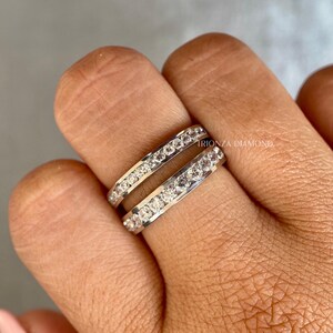 May include: A silver ring with two rows of clear round stones. The ring is on a person's finger. The text "TRIONZA DIAMOND" is visible on the ring.
