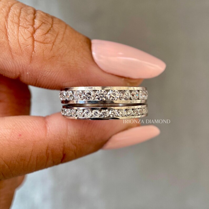 May include: A close-up of a silver ring with two rows of sparkling diamonds. The ring is held by a hand with pink nail polish. The text "TRIONZA DIAMOND" is visible in the lower right corner of the image.