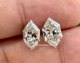 May include: Two clear, faceted, hexagonal diamonds with a pointed top and a rounded bottom. The diamonds are on a finger.