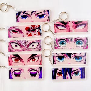 May include: A collection of rectangular keychains featuring anime-style eye designs. Each keychain displays a unique pair of eyes with varying colors and styles, attached to a silver keyring.
