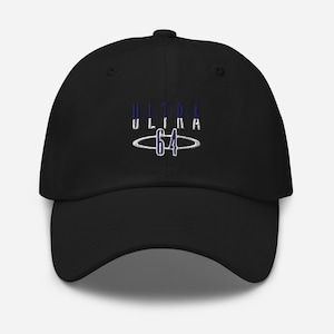 May include: A black baseball cap featuring an embroidered logo on the front. The design includes the word ULTRA in dark blue and white text, positioned above the number 64, which is encircled by a thin, horizontal white oval ring.
