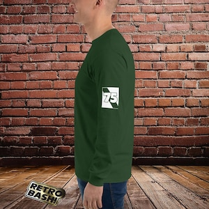 May include: A dark green long-sleeve shirt with a white patch on the left sleeve that says "75" in white text.