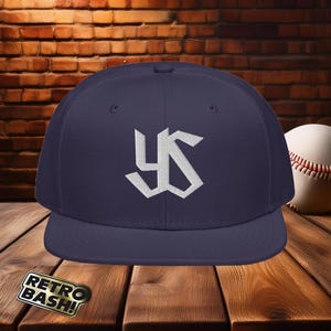 May include: A navy blue baseball cap with a white embroidered "YS" logo. The cap has a curved brim and a flat top.