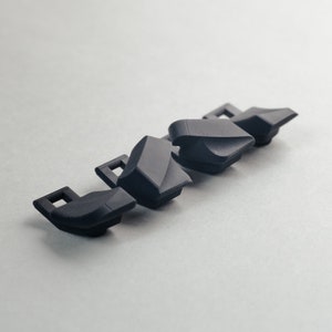 May include: Four black plastic keycaps with a textured surface and a square shape. The keycaps are designed for mechanical keyboards.