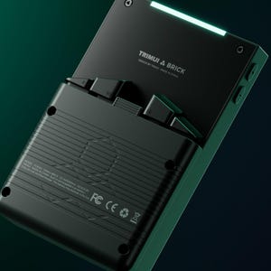 Peut inclure: Console de jeu portable noire avec le texte "TRIMUI & BRICK" et une lumi&egrave;re verte brillante. L'appareil a un design &eacute;l&eacute;gant et moderne avec des boutons et un &eacute;cran visibles. Le fond est un d&eacute;grad&eacute; de vert fonc&eacute; et de noir.