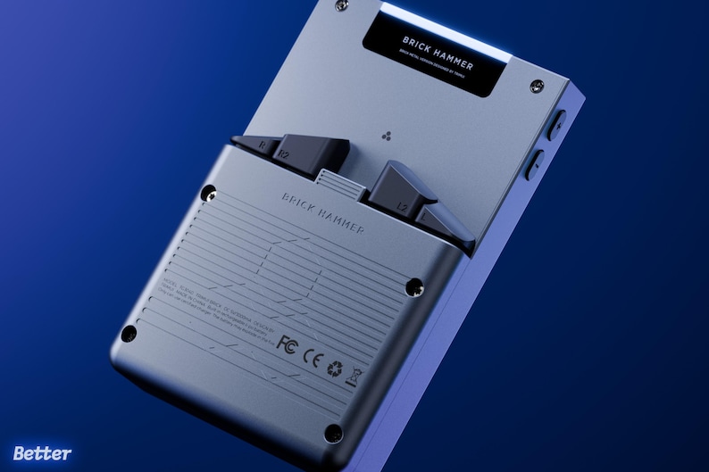 Peut inclure: Une console de jeu portable argent&eacute;e avec des boutons noirs et le texte "BRICK HAMMER". L'appareil a un design &eacute;l&eacute;gant et moderne avec un fond d&eacute;grad&eacute; bleu. Le texte "Better" est visible en bas &agrave; gauche.