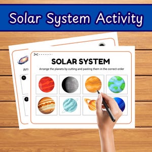 May include: A worksheet labelled "Solar System Activity" with the text "SOLAR SYSTEM" and instructions to arrange planets. The worksheet features colourful illustrations of planets. A hand is holding a pen, pointing to the planets.