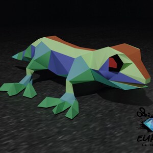 May include: A colourful, origami-style paper frog with a red eye. The frog is made of green, blue, and orange paper and is sitting on a black surface. The image includes the text "EUREKA 3D MAGICAL".