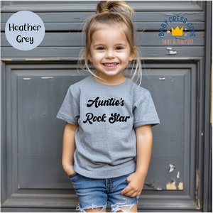 a little girl standing in front of a door wearing a t - shirt that says