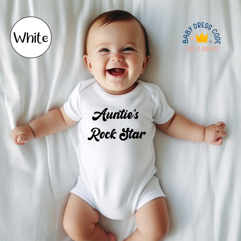 Puede incluir: Un body blanco para beb&eacute; con el texto "Auntie's Rock Star" en negro. El body est&aacute; sobre un fondo blanco.