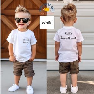 May include: Two white t-shirts for kids, one with the text "Coolest Wilson" and the other with the text "Little Sweetheart". Both shirts are worn by kids wearing brown shorts and white sneakers.