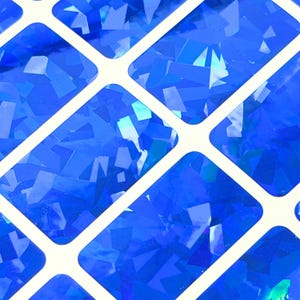 May include: A grid of rectangular stickers featuring a vibrant blue holographic finish. Each individual rectangle is separated by a thin white border, creating a repeating pattern of reflective, geometric shapes that catch the light.