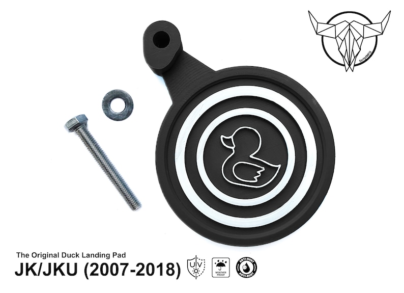 May include: Black rubber duck landing pad with a white duck silhouette and concentric circles. The pad is attached to a black metal bracket with a screw and washer. The text "The Original Duck Landing Pad JK/JKU (2007-2018)" is printed below the pad.
