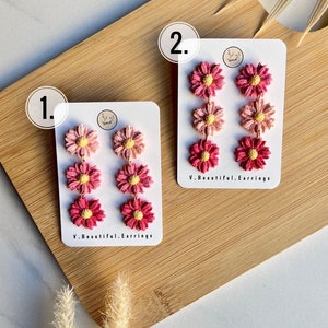 May include: Two pairs of pink and red flower dangle earrings on white cards with the text "V. Beautiful. Earrings" on each card. The cards are numbered 1 and 2.