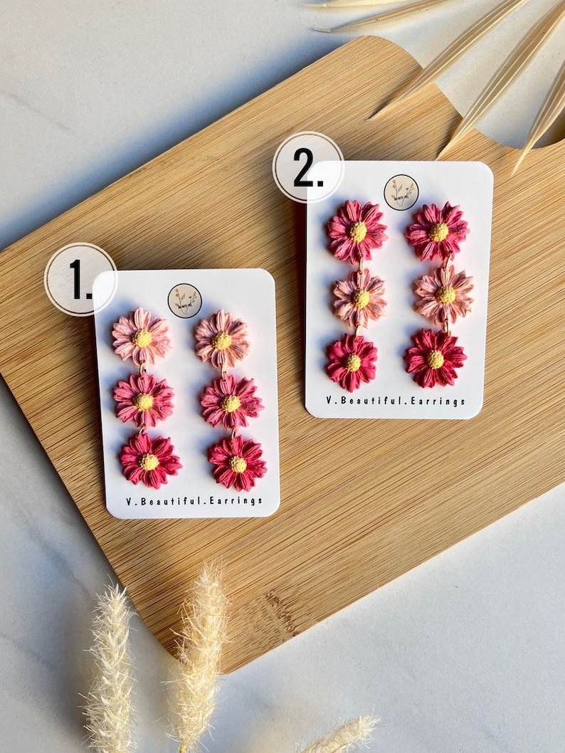 May include: Two pairs of pink and red flower dangle earrings on white cards with the text "V. Beautiful. Earrings" on each card. The cards are numbered 1 and 2.