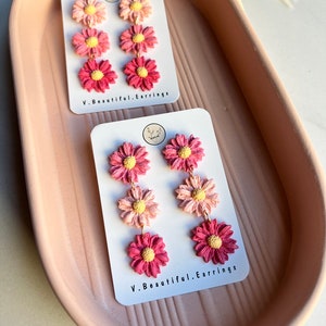 May include: A pair of pink and yellow flower dangle earrings on a white card with the text "V. Beautiful. Earrings".