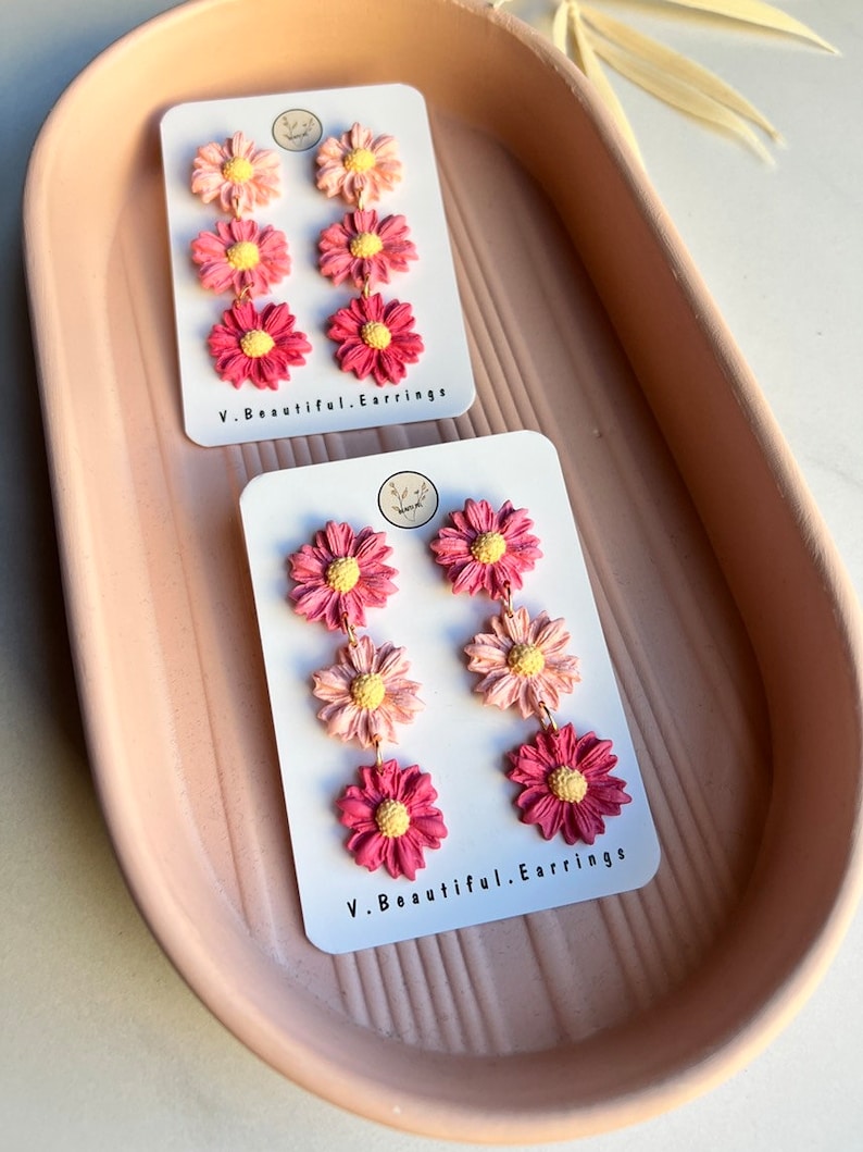 May include: A pair of pink and yellow flower dangle earrings on a white card with the text "V. Beautiful. Earrings".