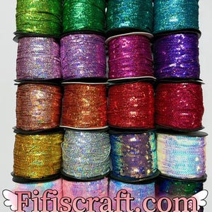 May include: Assortment of 15 spools of iridescent sequin trim in various colors, including green, purple, pink, gold, and blue. The spools are arranged in three rows of five. The text "Fifiscraft.com" is printed on the bottom of the image.