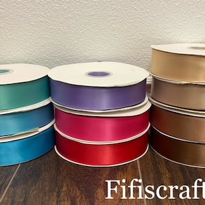 Puede incluir: Surtido de ocho carretes de cinta de satén en varios colores, incluyendo turquesa, azul, morado, rosa, beige, marrón y dorado. Los carretes están dispuestos en dos filas de cuatro, con el nombre de la marca "Fifiscraft.com" visible en la parte inferior de la imagen.