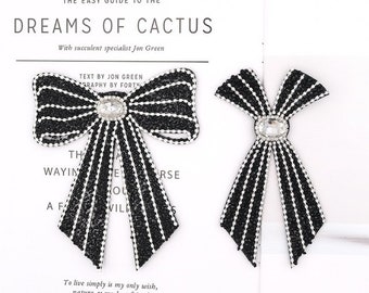 Puede incluir: Dos parches de tela en forma de lazo negro y blanco con pedrería y un cristal transparente en el centro. El texto "THE EASY GUIDE TO THE DREAMS OF CACTUS" está en la parte superior de la imagen. El texto "With succulent specialist Jon Green" está debajo de la primera línea de texto. El texto "TEXT BY JON GREEN" está por encima de los lazos. El texto "RAPHY BY FORTY" está debajo de la primera línea de texto. El texto "To live simply is my only wish, nature as my best friend" está debajo de los lazos. El texto "FifisCraft.com" está en la parte inferior de la imagen.