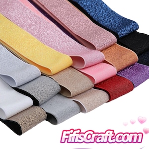 May include: A collection of folded elastic bands featuring a glittery, textured surface in various colors including white, silver, gold, yellow, pink, red, purple, blue, and black, with the text FifisCraft.com displayed in the bottom corner.