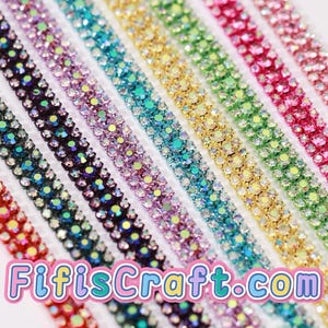May include: Rows of colorful rhinestone trim in various colors, including red, pink, green, gold, blue, purple, and black. The trim is arranged diagonally, showcasing the sparkling, iridescent stones. The text "FifisCraft.com" is at the bottom.