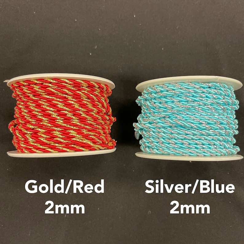 May include: Two spools of 2mm twisted cord. The left spool features red and gold metallic thread, while the right spool features light blue and silver metallic thread. Text below reads Gold/Red 2mm and Silver/Blue 2mm.