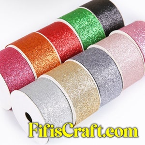 Puede incluir: Surtido de rollos de cinta de purpurina en varios colores, incluyendo rosa, naranja, rojo, verde, negro, gris, plata, oro y rosa claro. Los rollos están dispuestos en semicírculo con los extremos de los rollos superpuestos. El texto "FifisCraft.com" es visible en la parte inferior de la imagen.