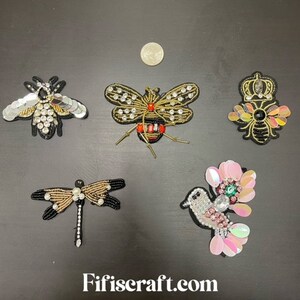 May include: Five embroidered iron-on patches featuring a bee, dragonfly, bird, and two bees with crowns. The patches are decorated with sequins, beads, and rhinestones.