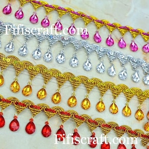 May include: Four rows of gold, silver, red, and pink trim with teardrop-shaped crystal embellishments. Each row has a different color trim and crystal.