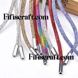 May include: Assortment of colorful rhinestone cords with silver metal tips. The cords are made of small rhinestones in various colors, including silver, gold, red, blue, and rainbow.