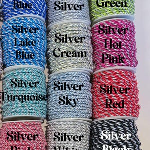 May include: Twelve spools of twisted cord arranged in a grid, each featuring a silver metallic thread intertwined with a solid colour. The colours include royal blue, silver, green, lake blue, cream, hot pink, turquoise, sky, red, pink, white, and black.