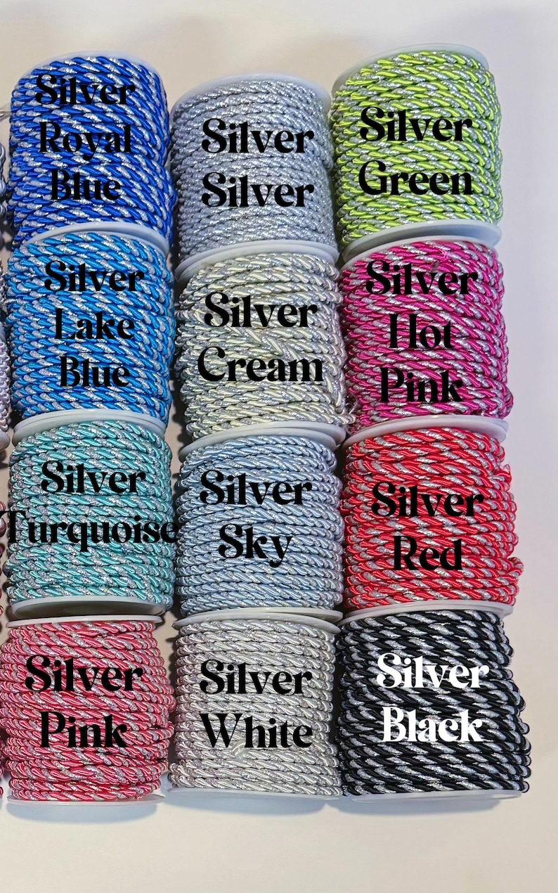 May include: Twelve spools of twisted cord arranged in a grid, each featuring a silver metallic thread intertwined with a solid colour. The colours include royal blue, silver, green, lake blue, cream, hot pink, turquoise, sky, red, pink, white, and black.