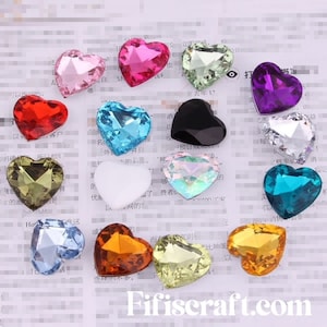 May include: Assortment of heart-shaped rhinestones in various colors, including clear, pink, green, purple, red, blue, orange, and iridescent. The rhinestones are arranged on a white background with Chinese text.
