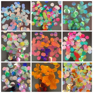 May include: Assortment of iridescent sequins in various colors, including blue, green, pink, orange, and purple. The sequins are round and have a metallic sheen.