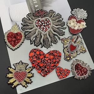 Könnte beinhalten: Sortiment aus sieben roten und goldenen herzförmigen Stickpatches mit Strasssteinen und Pailletten. Die Patches sind perfekt, um Kleidung, Taschen oder anderen Accessoires einen Hauch von Glanz zu verleihen.