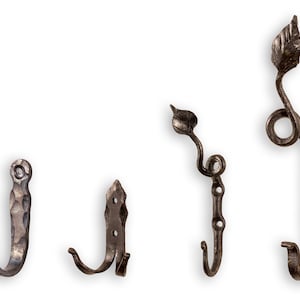 Könnte beinhalten: Vier verschiedene Arten von Metallhaken, jeder mit einem einzigartigen Design. Die Haken sind aus dunklem Metall und haben einen rustikalen Look. Zwei der Haken haben ein einfaches Design, während die anderen beiden ein aufwendigeres Design mit einem blattförmigen Detail haben.