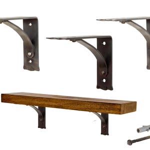 Op de afbeelding: Set van vier rustieke metalen plankdragers met een houten plank en montagemateriaal. De dragers zijn donkergrijs en hebben een decoratief ontwerp. De plank is gemaakt van natuurlijk hout en is ongeveer 45 cm lang.