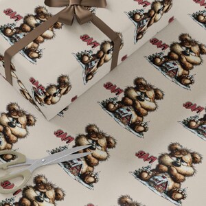 May include: Wrapping paper featuring a repeating pattern of a cartoon bear with a house in a snowy scene. The bear is brown with a grumpy expression. The word "SAM" is printed in red. A brown ribbon and scissors are also visible.