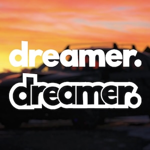 May include: An image with the word "dreamer" in white, stacked on top of each other, with a blurred silhouette of a vehicle in the background. The sky is a gradient of orange and yellow, suggesting a sunset or sunrise.