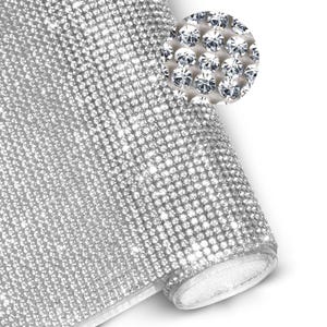 Può includere: Un rotolo di tessuto a rete argentato con strass. Il tessuto è densamente ricoperto di piccoli strass scintillanti, creando un effetto luccicante. Un inserto in primo piano mostra i singoli strass. Il rotolo è parzialmente srotolato.