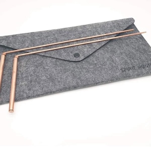 May include: A gray felt envelope with a button closure, holding two copper dowsing rods. The rods are straight with a right-angle bend near the handle. The text "SPIRIT HUNTER" is printed on the envelope.