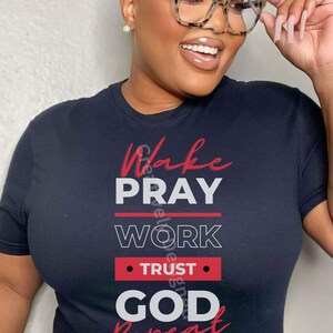 Peut inclure: T-shirt noir avec du texte rouge qui dit "Wake Pray Work Trust God Repeat".