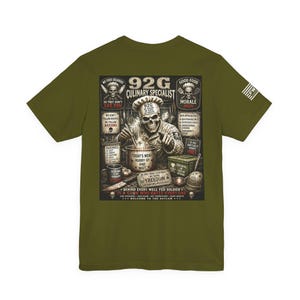 May include: An olive green t-shirt featuring a graphic on the back of a skeleton wearing a chef hat and military uniform, stirring a pot. The design includes text such as 92G CULINARY SPECIALIST, TODAY'S MENU HURRY UP AND WAIT, and other military-themed culinary phrases.