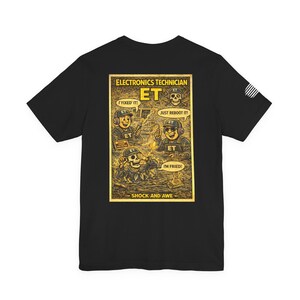 May include: Black t-shirt featuring a comic-style graphic with the text "ELECTRONICS TECHNICIAN." The graphic includes cartoon figures with the phrases "I FIXED IT!", "JUST REBOOT IT!", and "I'M FRIED!" The phrase "SHOCK AND AWE" is at the bottom.