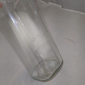 May include: A clear glass bottle with the embossed text "Kitchen Science". The bottle has a rounded base and a slightly tapered shape. The glass appears to be clean and free of any major imperfections.