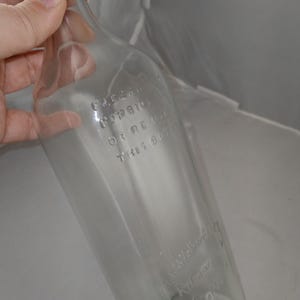 May include: A clear glass bottle with a wooden stopper. The bottle has embossed text that reads "ILLEGAL FORBIDDEN OR RE USE THIS BOTTLE" and "J. Walker & Co. Kilmarnock Scotland".